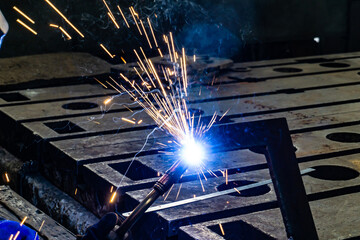 Sparks from electro gas welding at work in an electromechanical workshop.