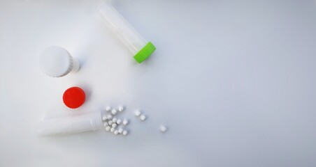 Homeopathic pills or medicines outside opened bottle in white background