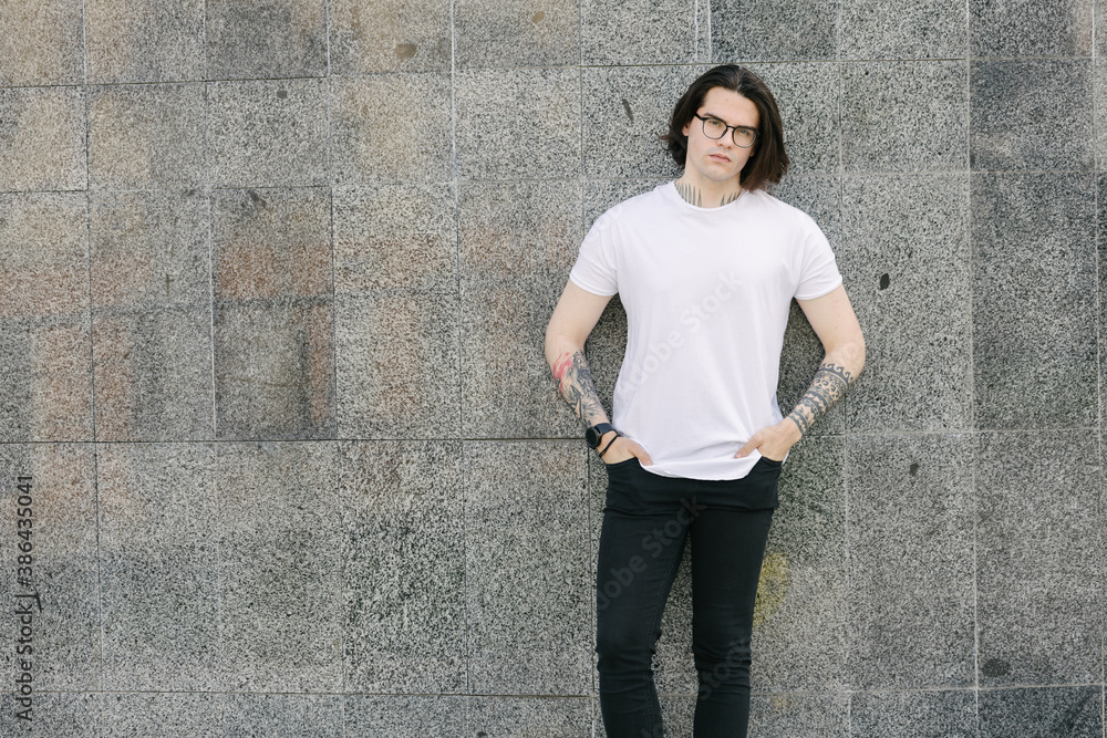 Poster hipster handsome male model with glasses wearing white blank t-shirt and black jeans with space for  - Posters