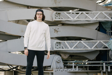 Man wearing blank white sweatshirt standing over gray background. Sweatshirt or hoodie for mock up, logo designs or design print with with free space.