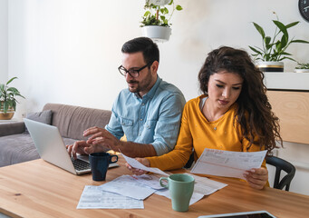 Worried couple calculating and paying bills online stock photo