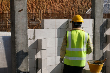 SEREMBAN, MALAYSIA -MARCH 16, 2020: Construction workers laying autoclaved aerated concrete block at the construction site. The use of this material can save time and facilitate construction work.