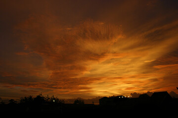 Dusk with yellow clouds. Silhouette of a building roof