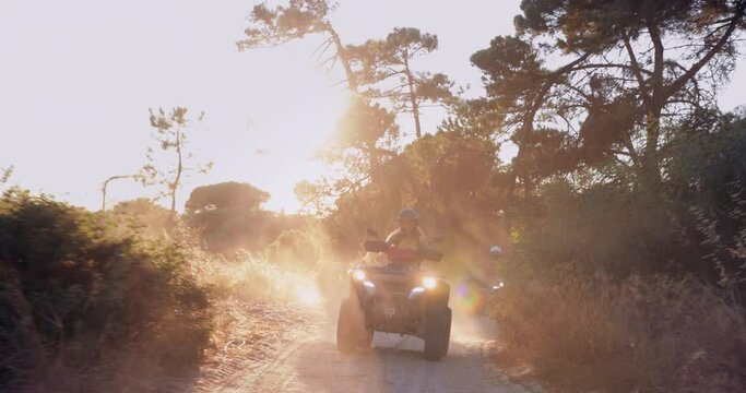 Woman riding quad bike in the sandy forest during sunset