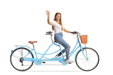 Young woman in casual clothes riding a tandem bicycle and waving