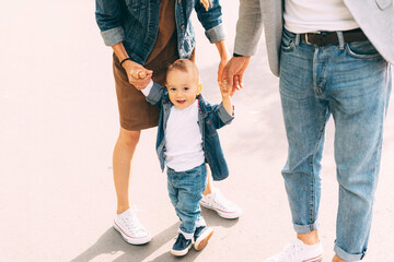 A cute little baby is learning how to walk near his parents