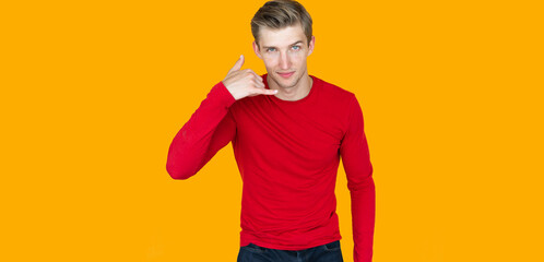 Fototapeta na wymiar young man of European appearance on a yellow background. raises his hand up and shows the phone with his finger.