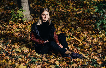 young woman autumn landscape red yellow maple leaves, in an orange knitted warm sweater