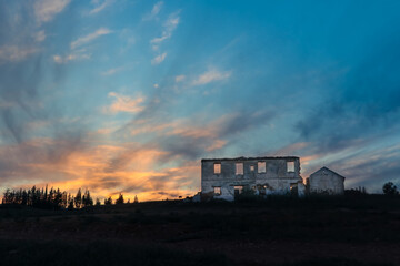 Fototapeta premium Atardecer con casa desenfocada en ruinas y bosque de pinos al fondo en Churriana, Málaga