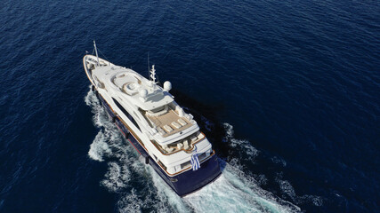 Aerial drone photo of luxury yacht with wooden deck cruising deep blue Aegean sea near island of...
