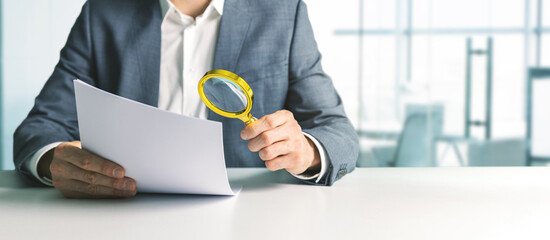 businessman or tax inspector analyzing document with magnifying glass in office. business financial...