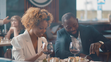 Portrait of cheerful beautiful afro-american couple dining in restaurant and talking