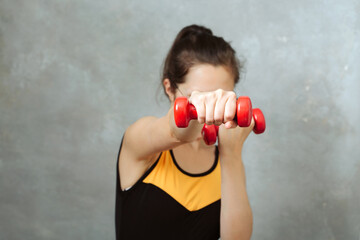 woman in sport wear beats hand with dumbbells to camera