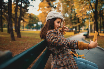 Teenage girl taking selfie in the park on autumn day