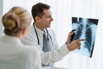 Doctor explaining  lung x-ray film of female patient at the hospital.