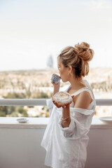 Fototapeta na wymiar young beautiful Asian girl in beige lace shorts,white shirt eating dessert, pie on the balcony. selective focus. small focus area.