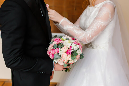 Wedding bouquet of roses in the hands of the groom in a suit