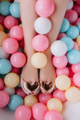 Fototapeta na wymiar Female feet in the bathtub with colorful balls 