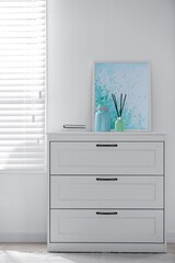 White chest of drawers near window in stylish room interior