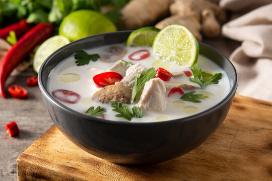 Traditional Thai food Tom Kha Gai in bowl on wooden table and ingredients.	