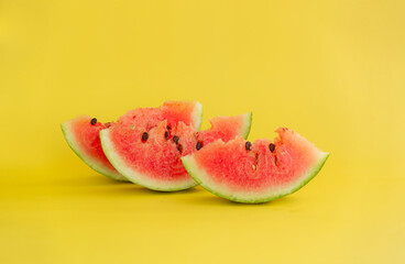 Cut red watermelon with seeds on a yellow background.