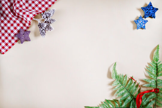 Christmas light background for photos with bead stars, green leaves with a red ribbon and forest cones.
