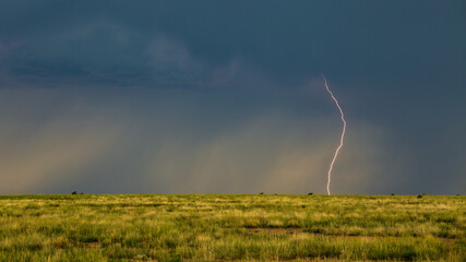 A lightning bolt strikes over an empty field as severe storms form in eastern Colorado