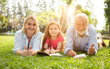 Parents and daughters are reading in the lawn at the weekend. A family reading on the grass.