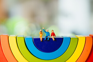 Miniature people, man and woman sitting on wooden rainbow using as business and social relationship...