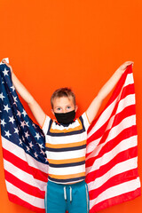 Portrait of a young boy wearing face mask with an american flag on orange background