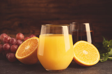 Glasses of delicious juices and fresh fruits on black table