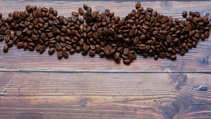 Roasted and aromatic Coffee beans on wooden table as background. Top view with and copy space for text. Macro photo of fresh arabica coffee beens. Copy