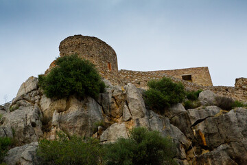View of beige castle defensive tower and eroded gray rocks