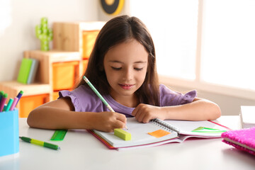 Little girl doing homework at table indoors