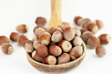 Big wooden spoon with great bunch of hazelnuts isolated on white background