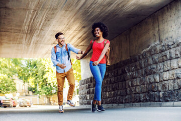 Cute happy multicultural couple running on the street.
