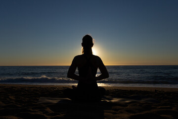 Caucasian woman doing stretching and yoga on Barceloneta beach in Barcelona
