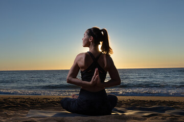 Fototapeta na wymiar Caucasian woman doing stretching and yoga on Barceloneta beach in Barcelona 