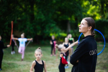 Coach leading the training in rhythmic gymnastics outdoors	