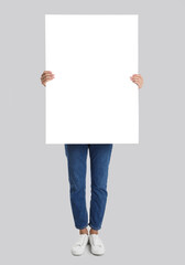 Woman holding blank poster on light grey background