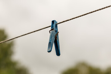 clothespin hanging from a rope. A clothespin hangs from the clothesline