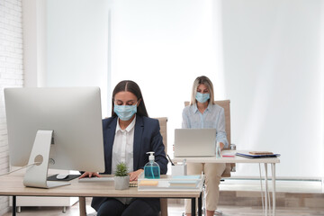 Office employees in respiratory masks at workplace