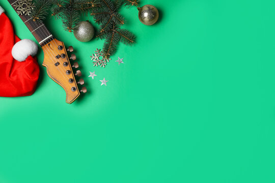 Christmas music. Flat lay composition with guitar and Santa hat on green background, space for text