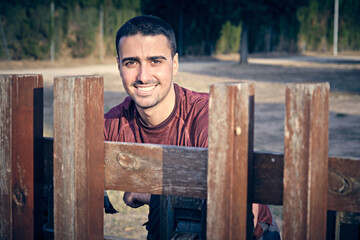 portrait of cheerful young man framed between pieces of wood