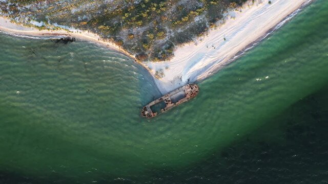 Aerial video flying over old shipwreck reinforced concrete barge abandoned stand on beach on the coast of Black sea in Kinburn peninsula, Ukraine. 4k UHD drone footage