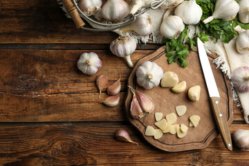 Fototapeta na wymiar Flat lay composition with fresh sliced and whole garlic on wooden table, space for text. Organic product