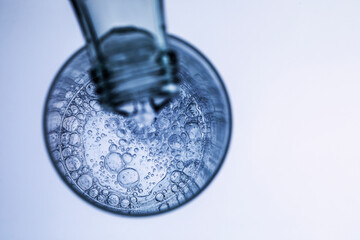 aus einer Glasflasche wir sprudelndes , klares Wasser in ein Glas geschenkt, Studioaufnahme