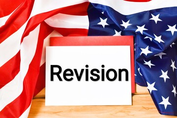 Fototapeta na wymiar REVISION written text in a notebook against the background of the American flag on a wooden background. Business concept. 