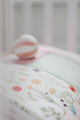 Cozy baby cot with pink patchwork blanket. Bedding and textile for children nursery. Photo of pink and white baby girl crib