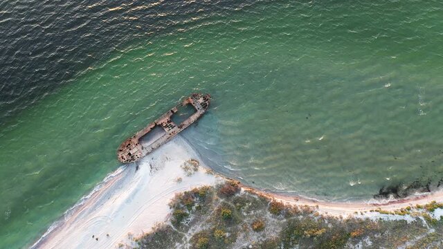 Aerial video flying over old shipwreck reinforced concrete barge abandoned stand on beach on the coast of Black sea in Kinburn peninsula, Ukraine. 4k UHD drone footage